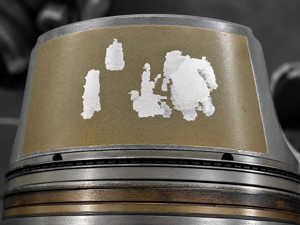 Porsche piston skirt with failed Ferroprint coating exposing aluminum before cylinder bore scoring